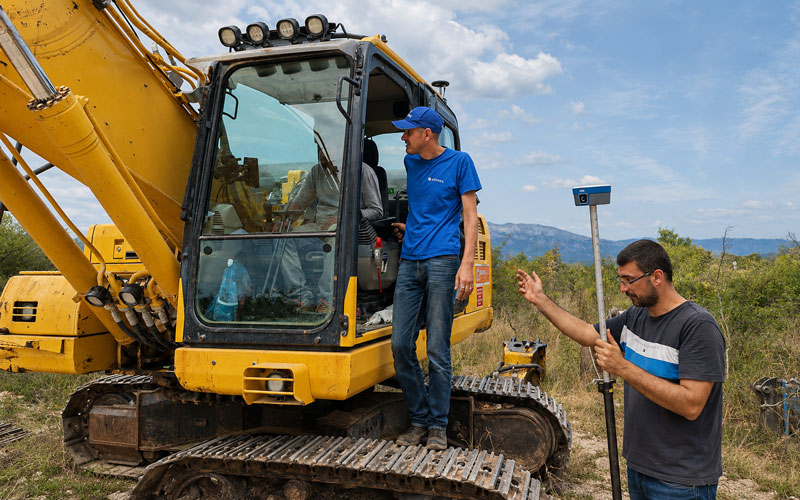Geodet sa STONEX GNSS prijemnikom uz građevinski stroj na terenu