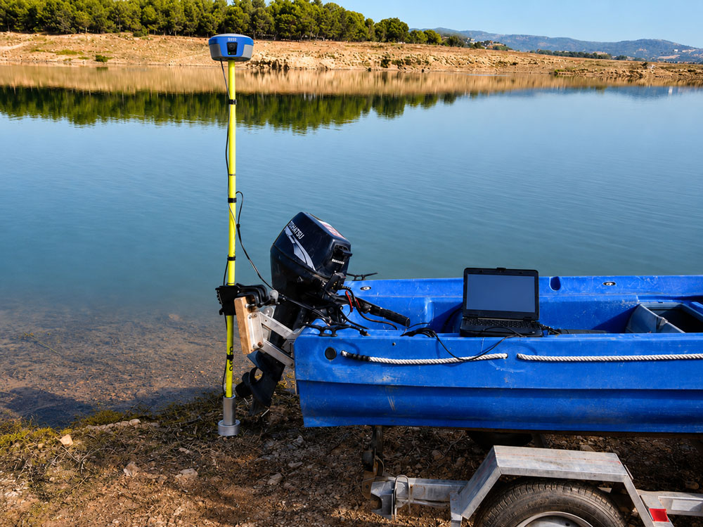 Hidrografsko plovilo na prikolici s GNSS antenom na žutom štapu i prijenosnim računalom uz jezero, spremno za batimetrijsku izmjeru